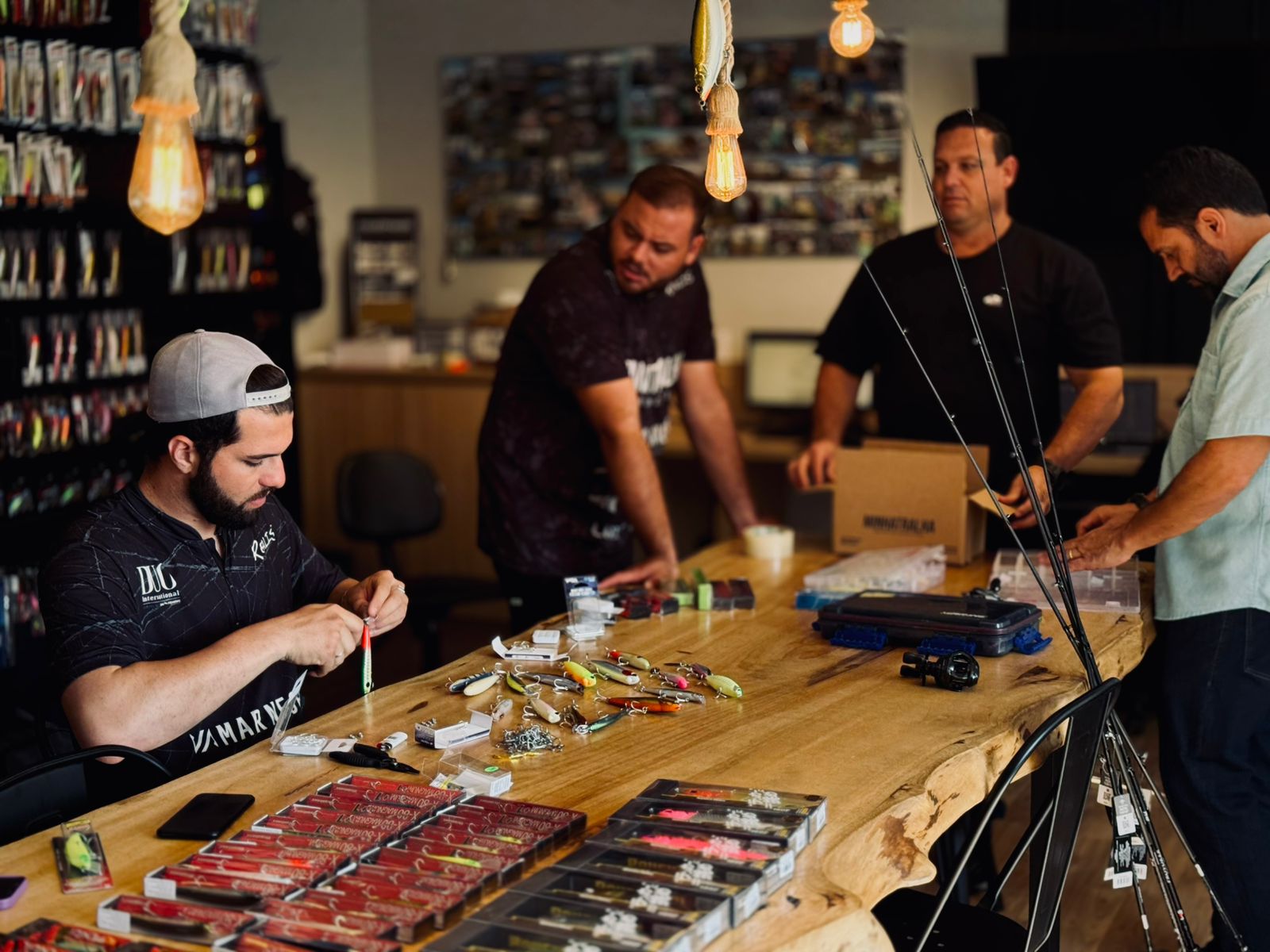 Consultores da Minha Tralha montando iscas e equipamentos em volta de uma mesa de pesca